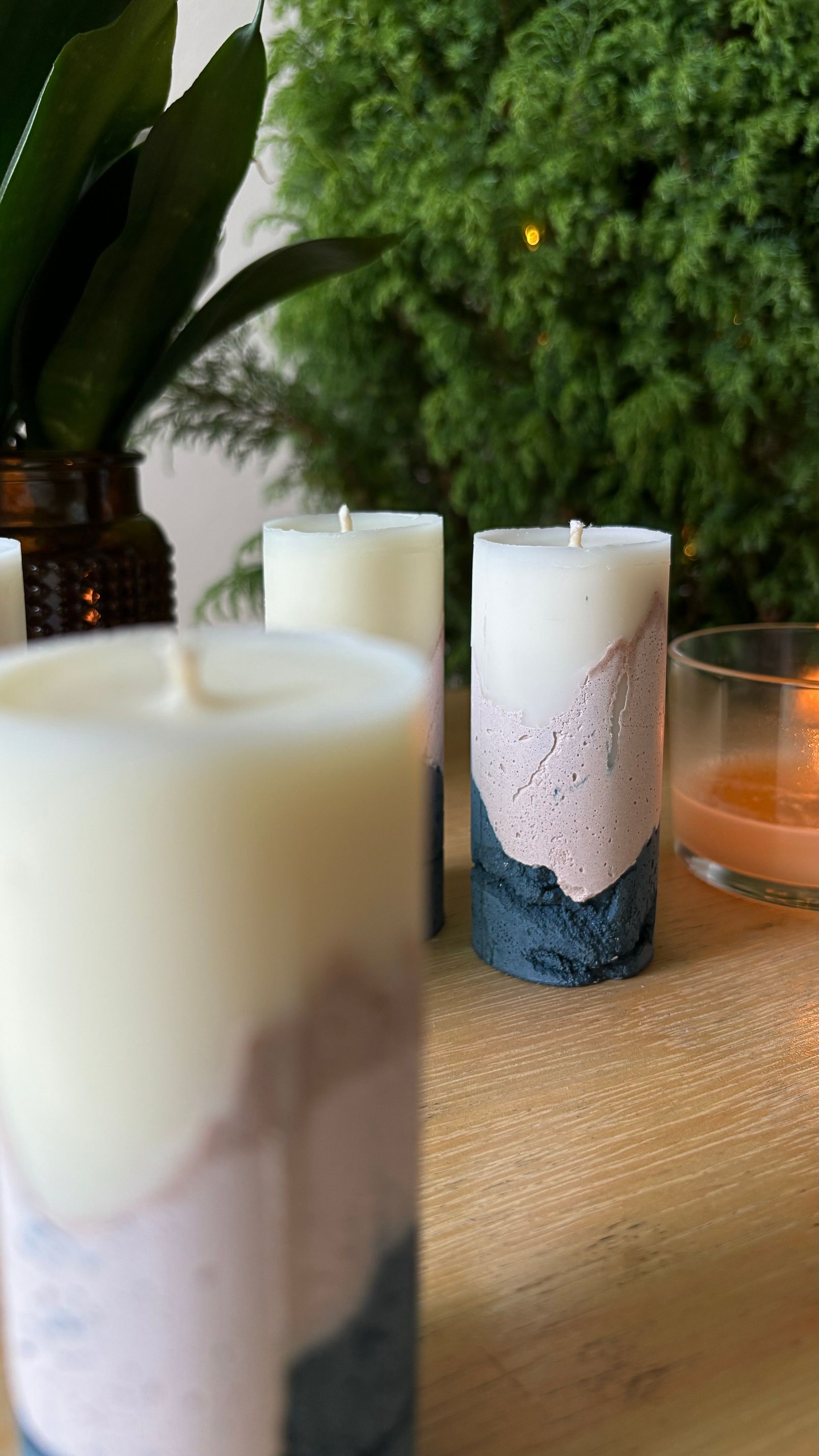 Velas com base de concreto rosa e grafite sobre uma mesa de madeira